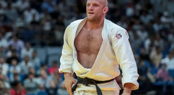 Marcus Nyman, en svensk judoka, står på mattan i sin vita dräkt med svart bälte. Publiken syns i bakgrunden.