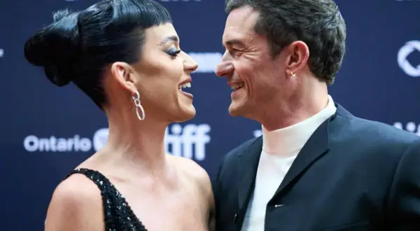 Katy Perry i Orlando Bloom patrzą na siebie z uśmiechem na czerwonym dywanie.