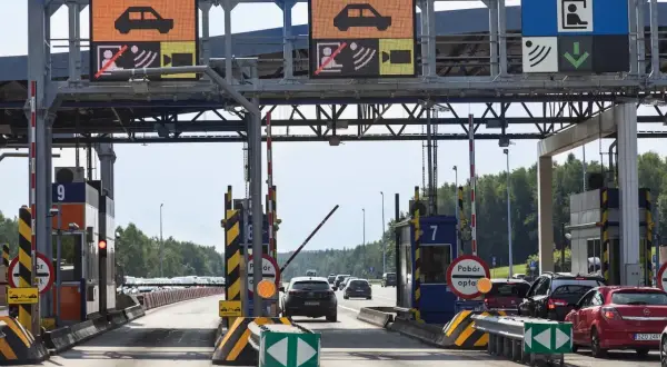 Kolejka samochodów na bramkach autostradowych. Jeden z pojazdów, jakby chciał wystartować w wyścigu dragster, czeka na zielone światło.
