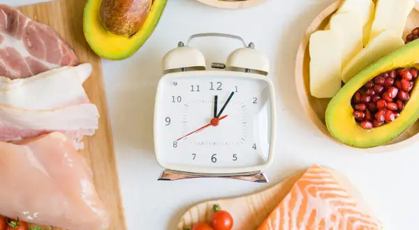 Zegar tyka, wskazując czas na dietę if. Mięso, ryby, awokado i orzechy czekają na zdrowe posiłki.