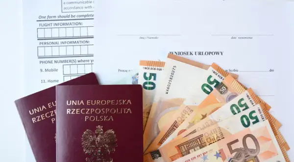 Paszporty i euro leżą obok wniosku urlopowego. Czy urlop okolicznościowy przepada, gdy brakuje środków na podróż?