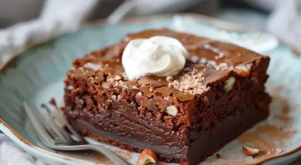 En saftig brownie med hasselnötter, toppad med vispad grädde. Perfekt för ett gott fudge brownie recept.