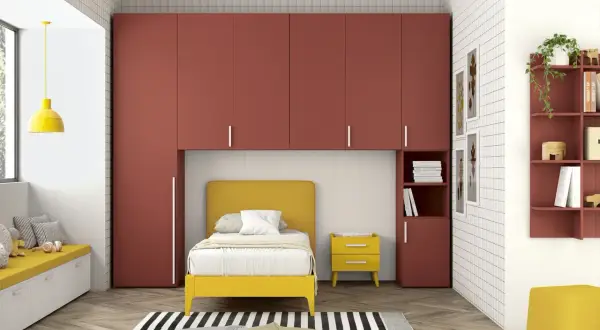 Soluzione moderna per organizzare armadio a ponte bambini: letto giallo, contenitori a muro rossi e seduta imbottita.