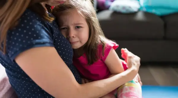 Mała dziewczynka z płaczem tuli się do mamy, przeżywając lęk separacyjny.