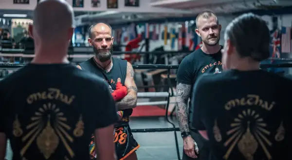 Tränare och fighters i en ring, alla bär tröjor med texten "onechai muaythai".