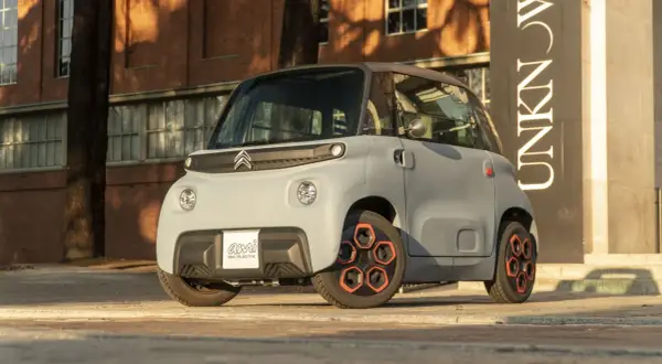 Citroën Ami, un veicolo elettrico compatto, mostra le sue prestazioni urbane con un design audace e ruote arancioni.