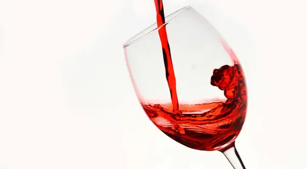 Czerwone wino, niczym reserva especial, wylewa się do kieliszka, tworząc wirujące fale.