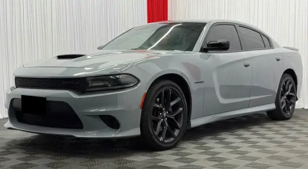 Szary Dodge Charger Hellcat z czarnymi felgami i przyciemnianymi szybami stoi na kratkowanej podłodze.