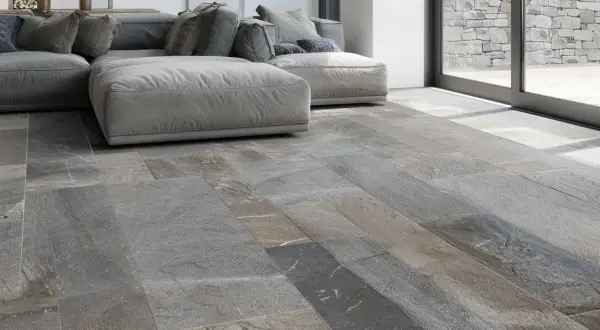 Pavimento in pietra di Luserna, grigio e variegato, con un divano moderno. Ideale per chi cerca consigli su come pulire la pietra di Luserna.