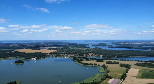 Krajobraz z lotu ptaka, gdzie widać liczne jeziora i lasy, tworzące malowniczą krainę tysiąca jezior.