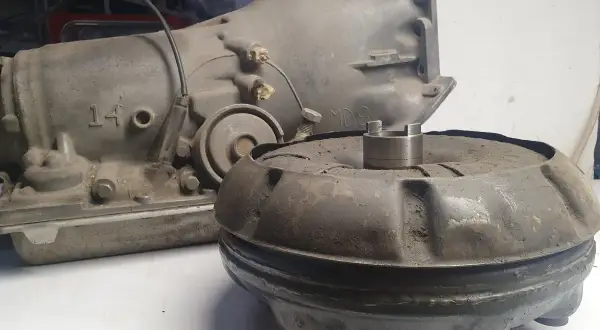 Zardzewiały sprzęgło hydrokinetyczne i skrzynia biegów leżą na stole.
