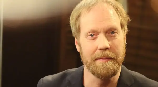 Lars Johan Åge, en man med blont hår och skägg, blickar mot kameran.