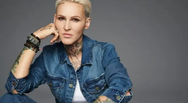 Agnieszka Chylińska w dżinsowej kurtce, z tatuażami i bransoletkami, w pozie sugerującej "never ending sorry".