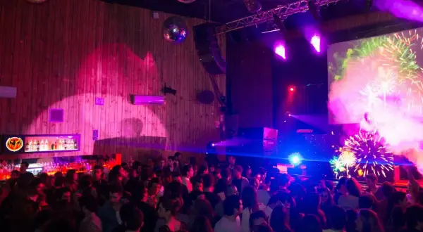 Festa al Macarena Club Barcelona, con luci stroboscopiche, DJ e fuochi d'artificio sullo schermo.