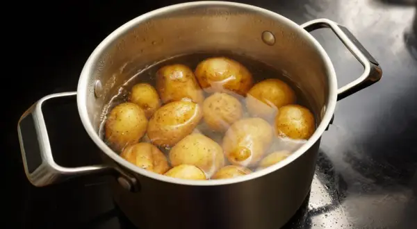 Ein Topf mit vielen Kartoffeln, die in Wasser kochen. Sind Kartoffeln gesund? Ja, sie sind eine gute Quelle für Vitamine und Mineralstoffe.