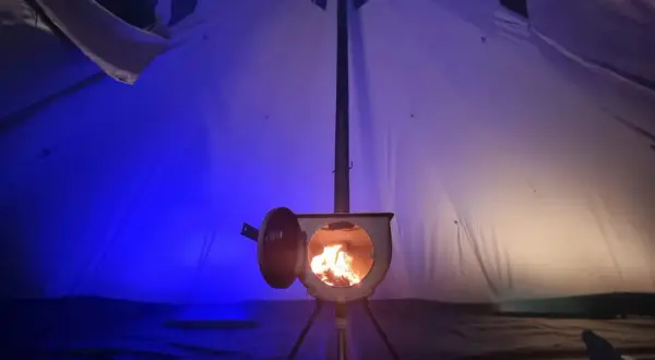 Wnętrze namiotu z palącym się piecykiem. To idealne ogrzewanie do namiotu, które tworzy przytulną atmosferę.