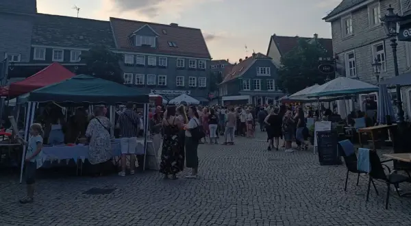 Menschen genießen den Abend auf dem Markt Remscheid. Stände mit Zelten und Tische unter Sonnenschirmen laden zum Verweilen ein.