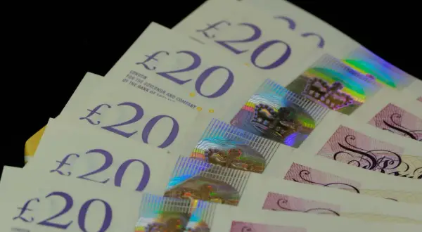 Kilka banknotów 20 funtów aktualnych, ułożonych w wachlarz. Widać holograficzne korony i napisy.
