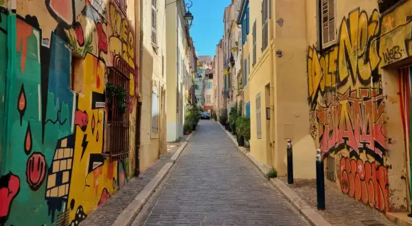 Kolorowa uliczka z brukowaną nawierzchnią, ozdobiona dynamicznym street art graffiti na ścianach budynków.