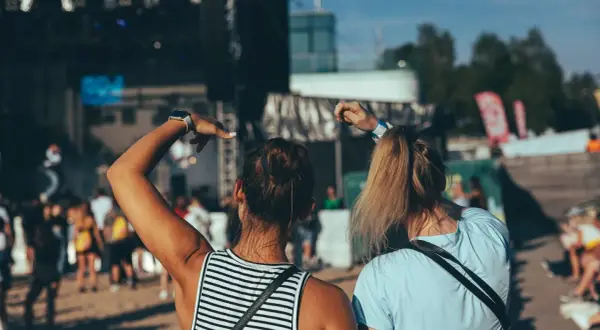 Dwie dziewczyny bawią się na koncercie podczas zielonego festiwalu, unosząc ręce w rytm muzyki.
