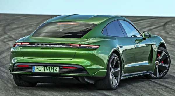 Zielony Porsche Taycan 4S z polskimi tablicami rejestracyjnymi PO-1NU14 na tle pustej drogi.