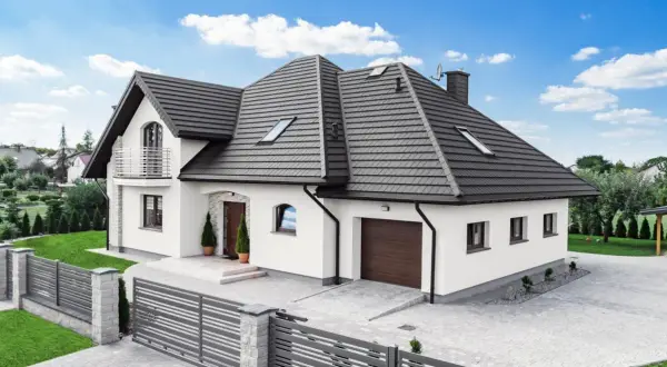Nowoczesny dom z szarym ogrodzeniem wokół posesji, z kamiennymi słupkami i metalowymi przęsłami.