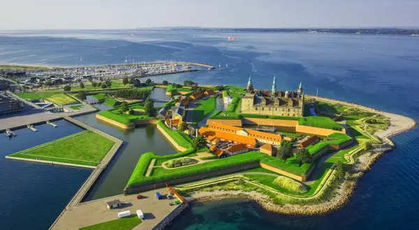 Kronborgs slott vid havet, en stjärnformad fästning med vallgravar och gröna ytor. En idyllisk vy över december i Danmark.