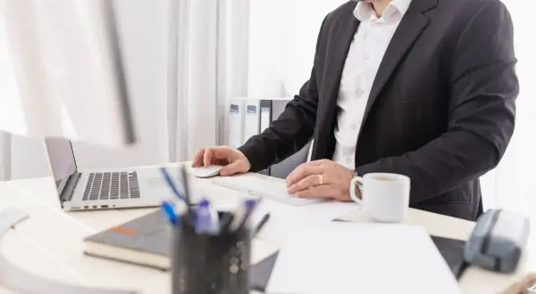 Biznesmen przy biurku, pracujący przy laptopie i klawiaturze. Może to być związane z wpłatą gotówki na konto firmowe.