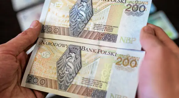 Dwie ręce trzymają banknoty 200 zł. Chcesz wiedzieć, jak wyprostować banknot? Oto rozwiązanie.