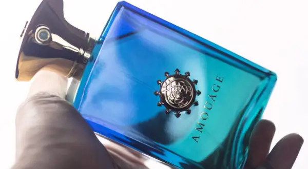 Dłoń trzyma luksusowe perfumy Amouage Figment w niebiesko-turkusowej butelce.