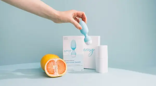 Main d'une femme tenant une sonde pour rééducation périnéale. Le produit, une sonde pour rééducation périnéale, est présenté avec des fruits. Pas d'effets secondaires connus.