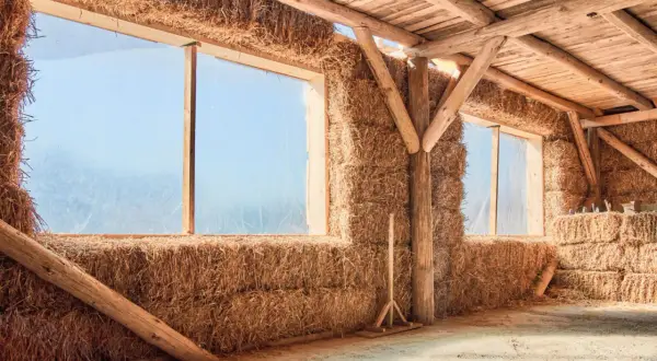 Interno di una struttura con pareti di balle di fieno e tetto in legno. Un esempio di costruzione con materiali ecosostenibili.