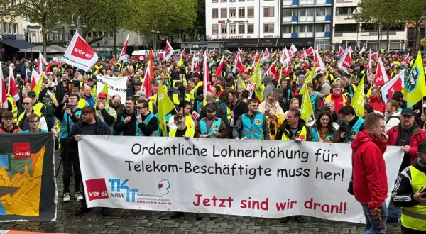 Große Menschenmenge bei einem Telekom-Streik. Sie fordern "Ordentliche Lohnerhöhung für Telekom-Beschäftigte muss her!". Viele Fahnen und gelbe Westen sind zu sehen.