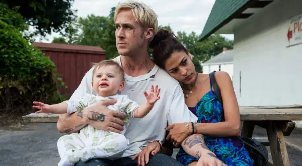 Ryan Gosling barn i famnen, med Eva Mendes vid sin sida. En stund av familjefrid trots omgivningen.