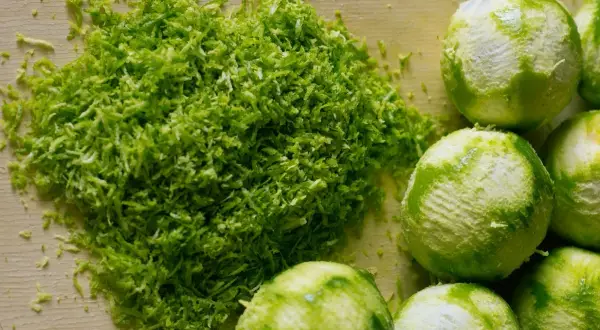Świeżo starta skórka z limonek, idealna do domowego kordiału. Obok leżą obrane limonki.