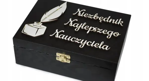Czarna szkatułka z piórem i kałamarzem, ozdobiona napisem "Niezbędnik Najlepszego Nauczyciela". Idealna dedykacja dla nauczyciela.