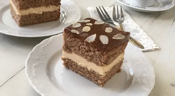Pyszne ciasto z mascarpone i kajmakiem, polane czekoladą i posypane płatkami migdałów. Idealne na deser.