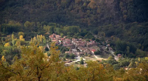 Un pueblo de tejados rojos se asoma entre la arboleda otoñal. La acebeda, un lugar tranquilo rodeado de naturaleza.