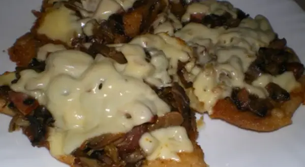 Schab w plastrach pieczony w piekarniku z pieczarkami i serem, danie wygląda apetycznie i jest gotowe do podania.