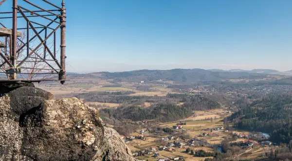 Widok z punktu widokowego na rudawy janowickie. W dole malownicza dolina z zabudowaniami i lasami.