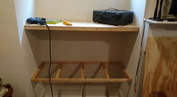 DIY project: a drill, level, and audio receiver sit on a wooden shelf, with a frame for another shelf below, showing how to hang shelves.