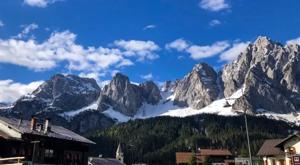 Villaggio alpino con case in legno e montagne innevate sullo sfondo. Un assaggio di cosa vedere in Carnia, tra natura e tradizione.