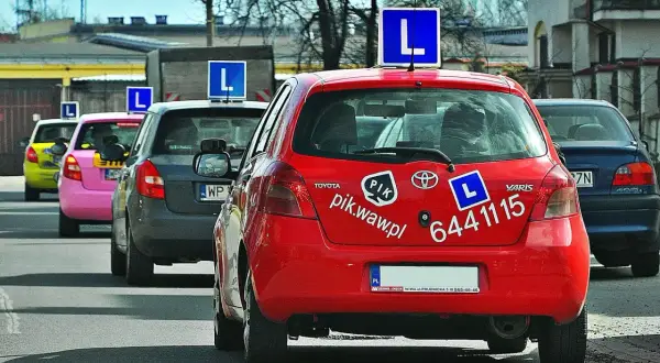 Czerwony samochód nauki jazdy z literą "L" na dachu. Zastanawiasz się, ile zarabia instruktor jazdy konnej?