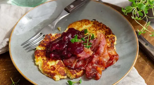 Stekta potatisbullar av potatismos toppas med lingonsylt och knaperstekt bacon. En klassisk svensk rätt som väcker aptit.