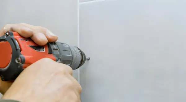 Mani esperte usano un trapano per forare la ceramica senza romperla, mostrando la tecnica corretta.