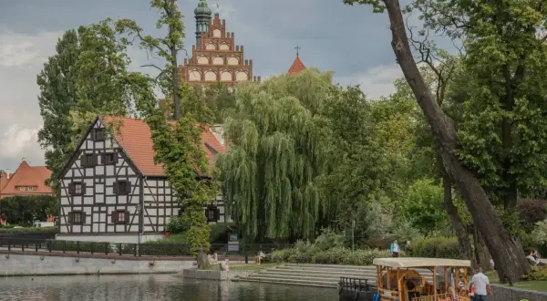 Nietypowe atrakcje Bydgoszcz: malowniczy widok na Brdę z zabytkową architekturą i łodzią.