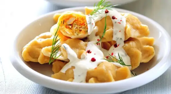 Pyszne pierogi z mięsem na imprezę, polane sosem i posypane koperkiem i pieprzem. Idealne na każdą okazję!