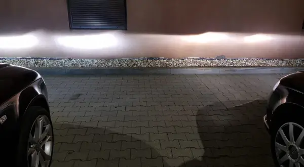 Jasne światła z przodu Audi A4 B6 oświetlają ścianę.