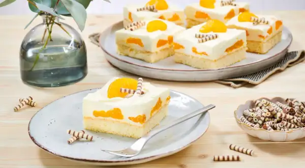 Saftiger Mandarinen Schmand Kuchen Blech, dekoriert mit Mandarinenstücken und Schokoröllchen. Ein Genuss für Augen und Gaumen!