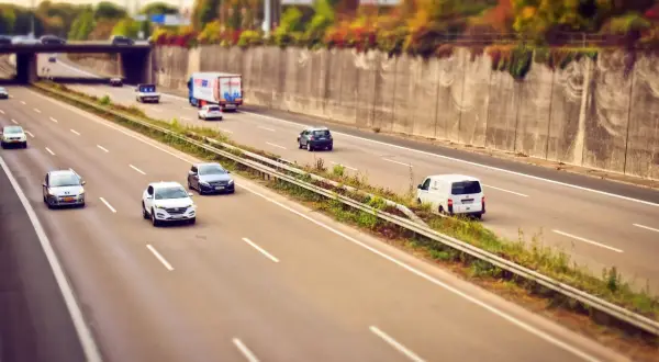 Voitures et camion circulent sur l'autoroute A85, sous un pont, avec des arbres aux couleurs d'automne sur les talus.